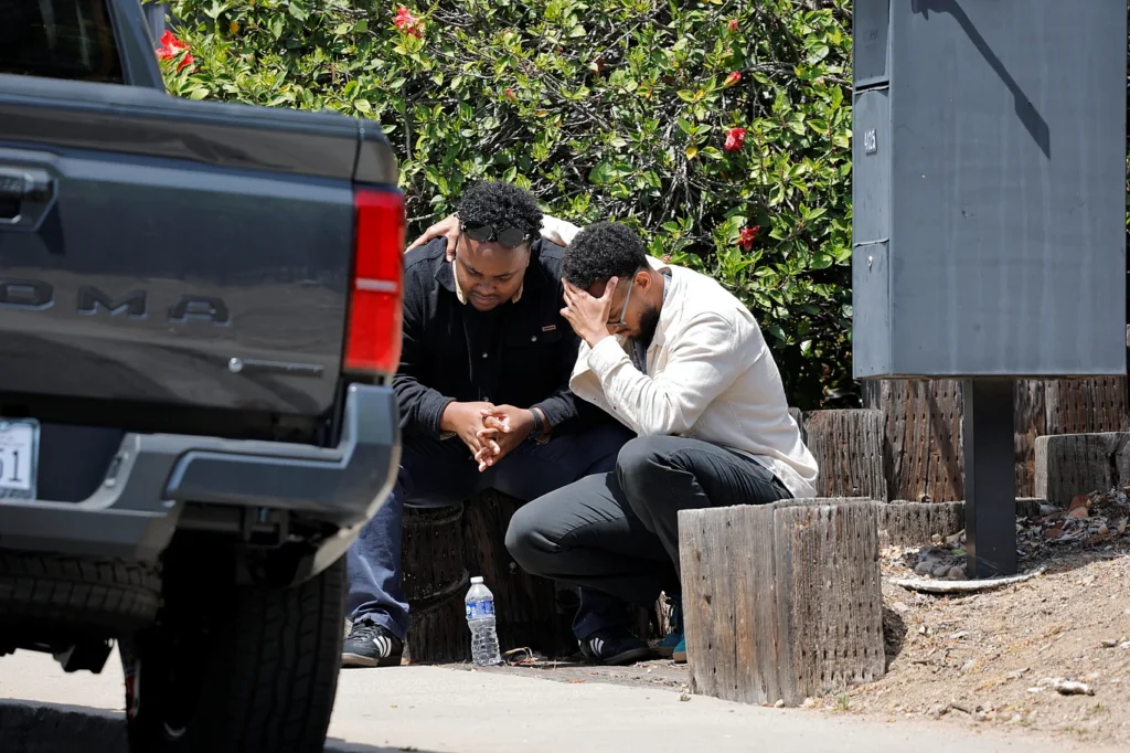 Two individuals sit on a sidewalk near the scene, comforting each other after receiving news of a gun attack at an Islamic center in San Diego, California, USA. May 18, 2026. Photo: Reuters.