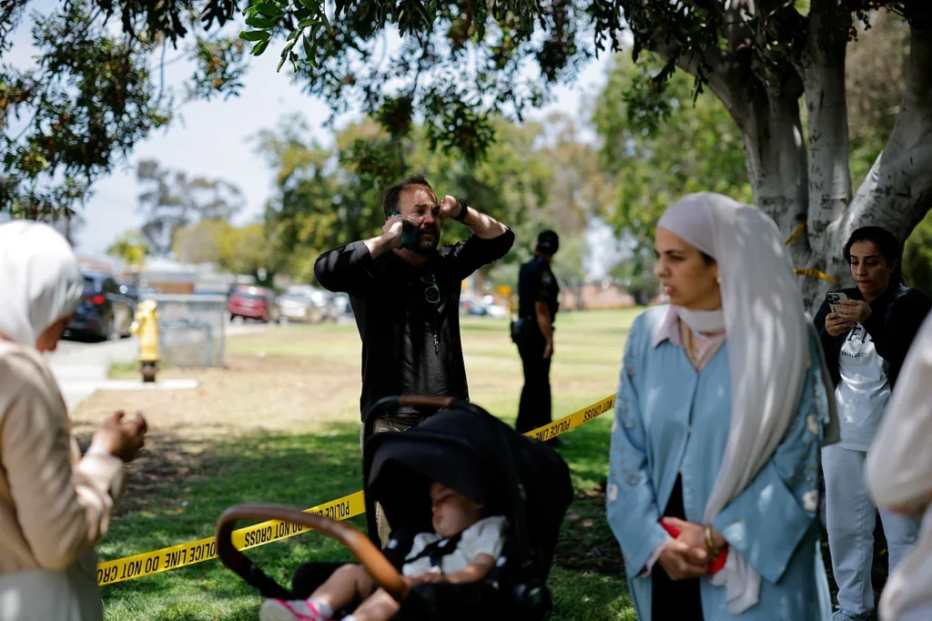 After receiving reports of a gun attack at an Islamic center in San Diego, California, security forces cordoned off the area with yellow tape. Nearby, men and women waiting for news of their loved ones are speaking on their mobile phones. May 18, 2026. Photo: Reuters.